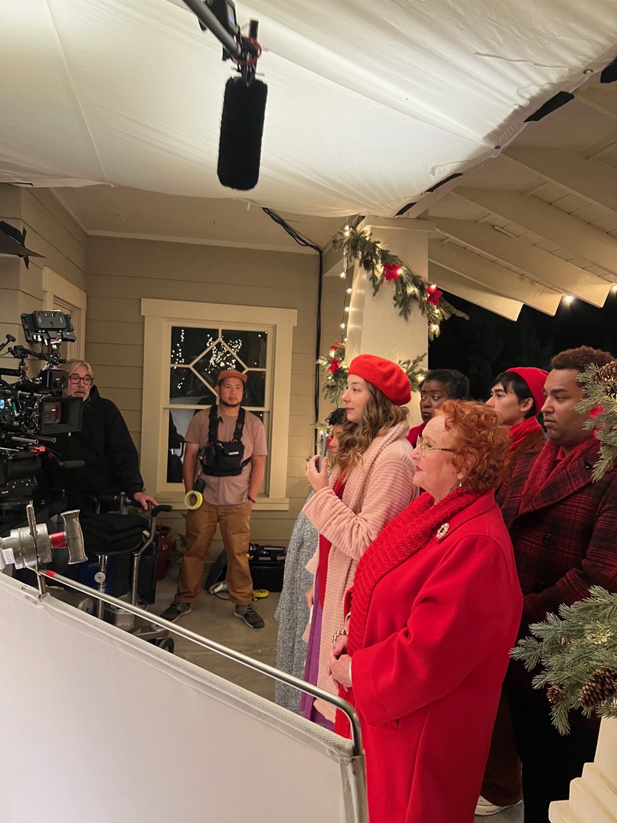 Carolers singing on the Verizon set, boom mic and camera in frame.